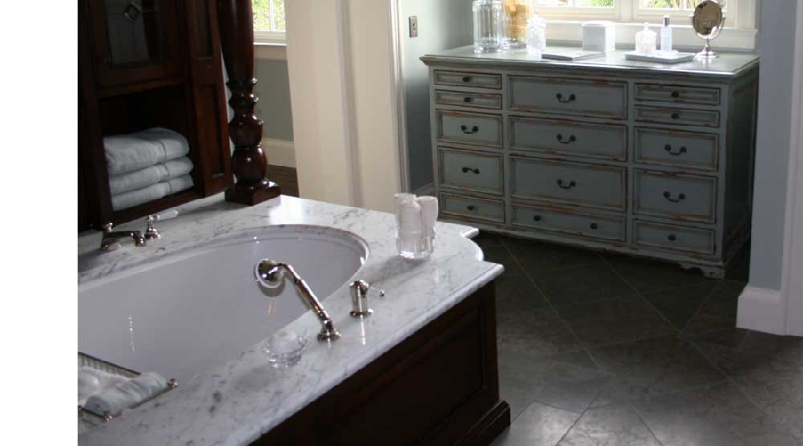 Painted dresser-style vanity in distressed grey-blue with marble soaking tub surround, Laguna Beach