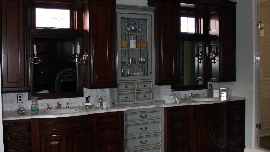 Traditional double vanity in dark cherry with marble countertop, glass-front upper cabinets, and wall sconces, Newport Beach