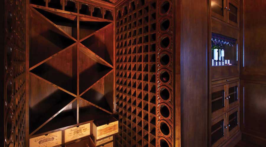 Custom wine cellar with diamond bottle rack, round bottle inserts, and carved dark walnut columns