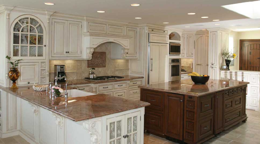Traditional antique white kitchen with carved corbels, arched glass display panels, and contrasting walnut island, Newport Beach