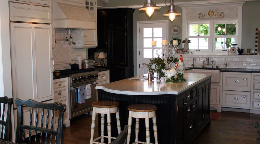 Farmhouse kitchen with painted black island, white cabinets, subway tile, and pendant lights, Laguna Beach