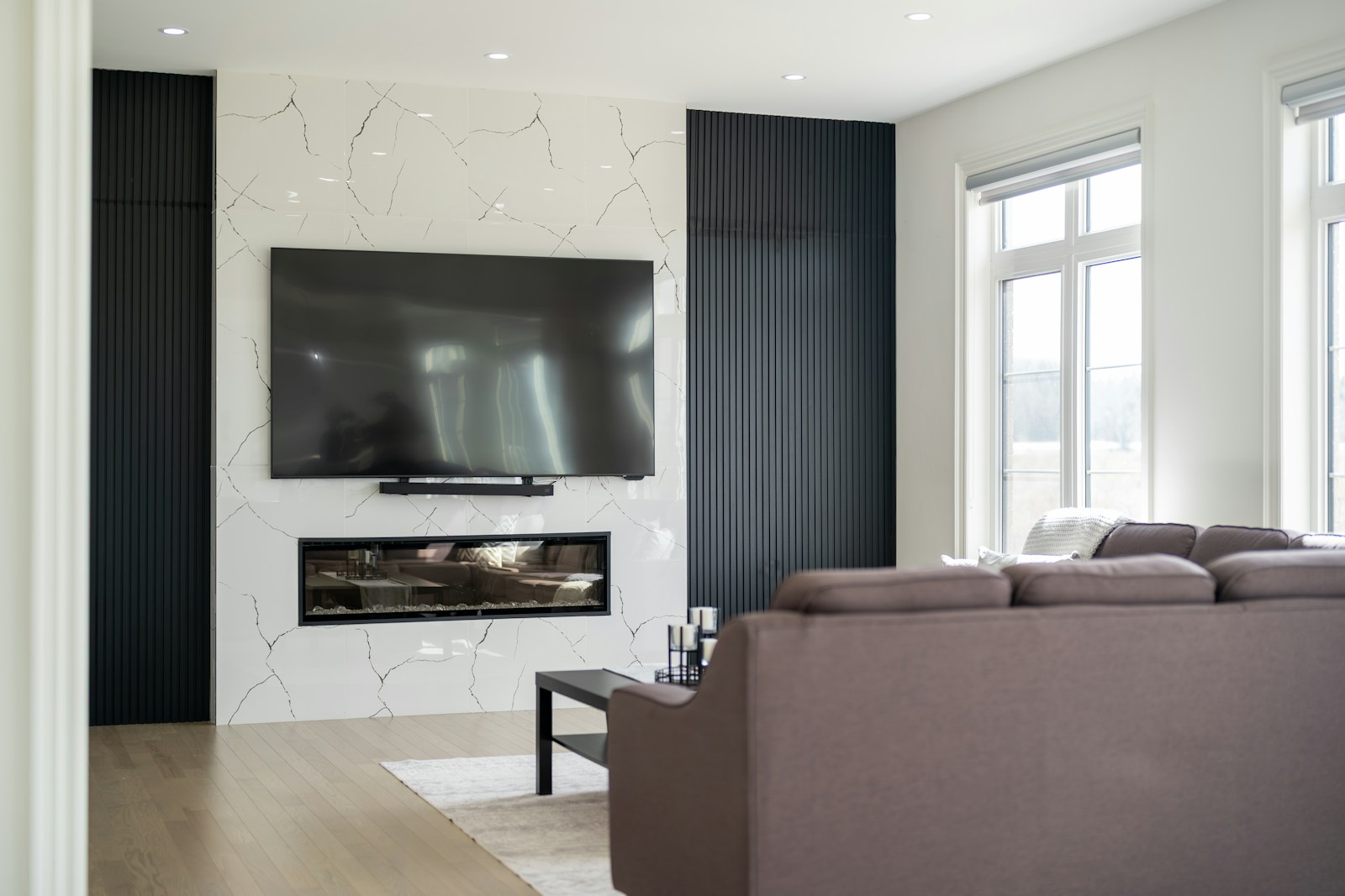 Luxury TV cabinet in a marble and wood media room with modern fireplace