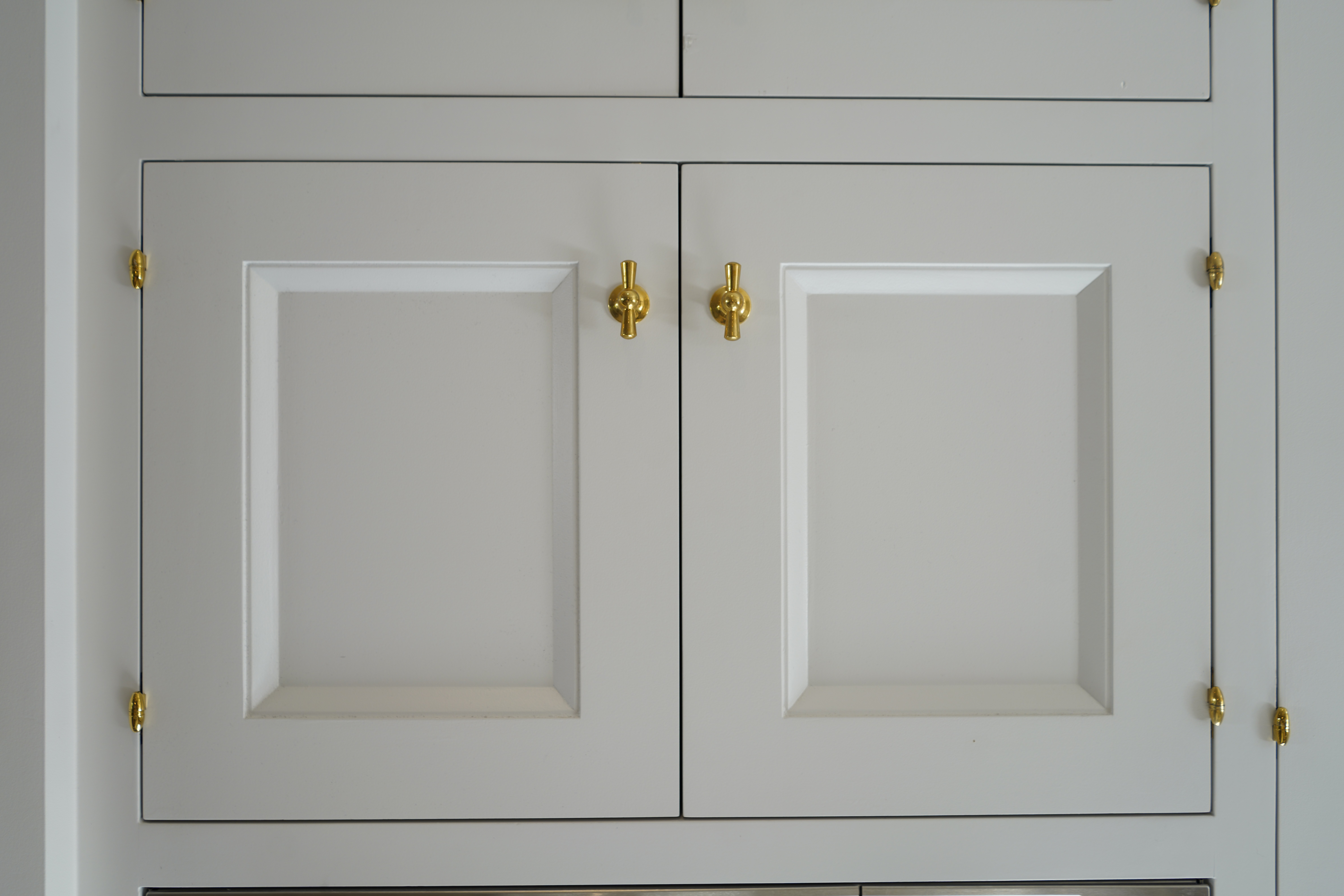 Custom white kitchen cabinet door brass tee knob detail