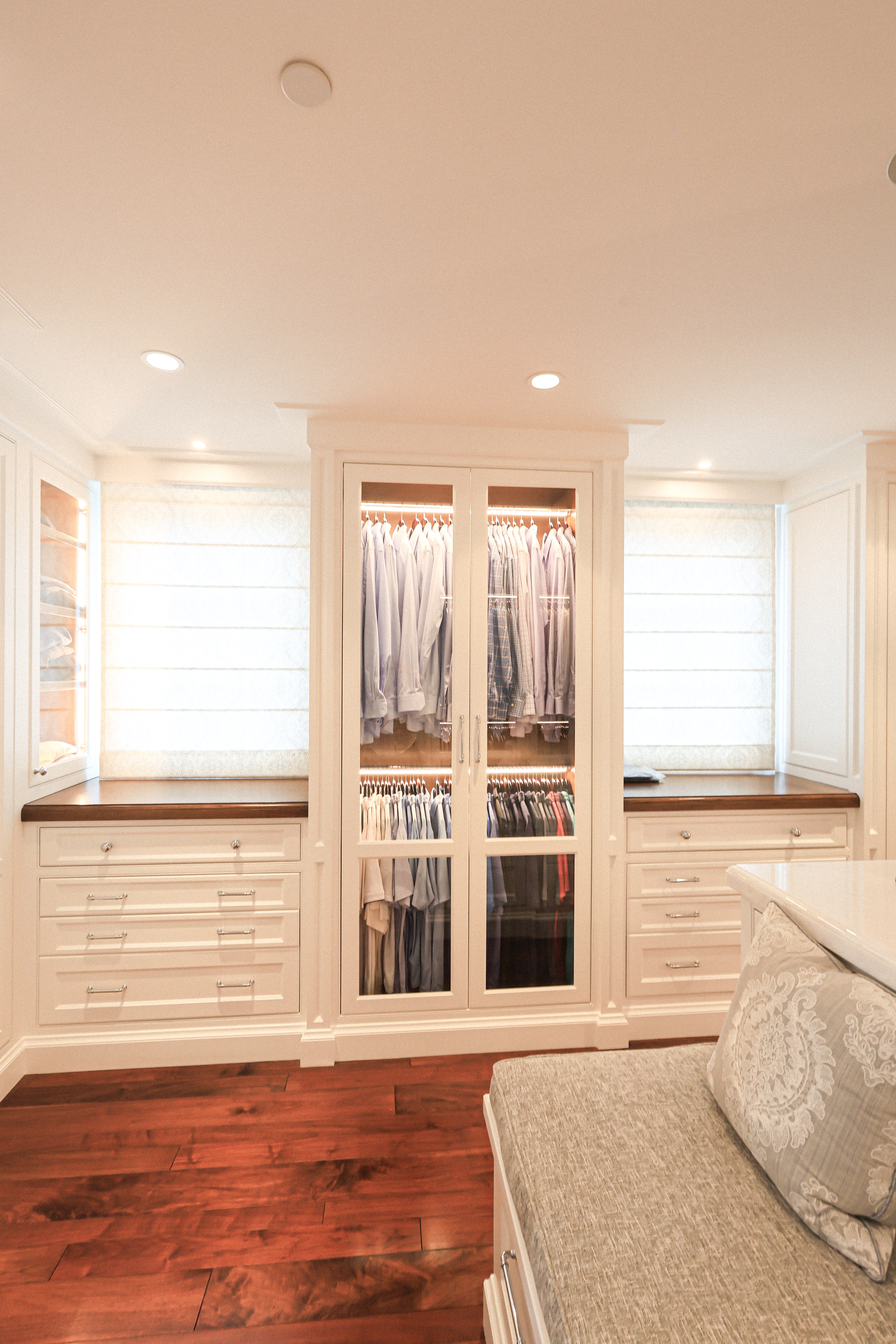 Custom his master closet white glass-front built-in cabinetry