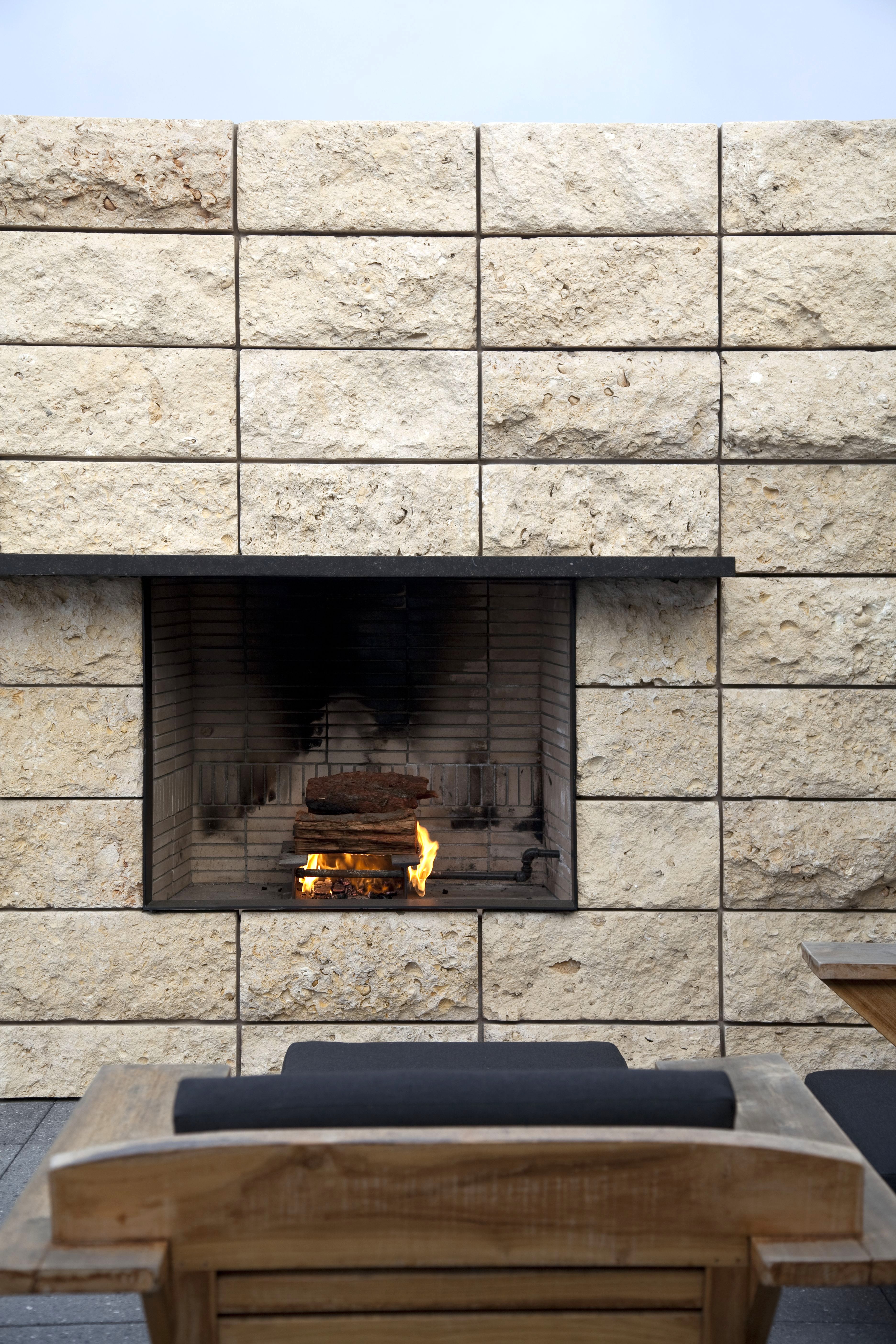 Newport Beach outdoor stone fireplace burning night
